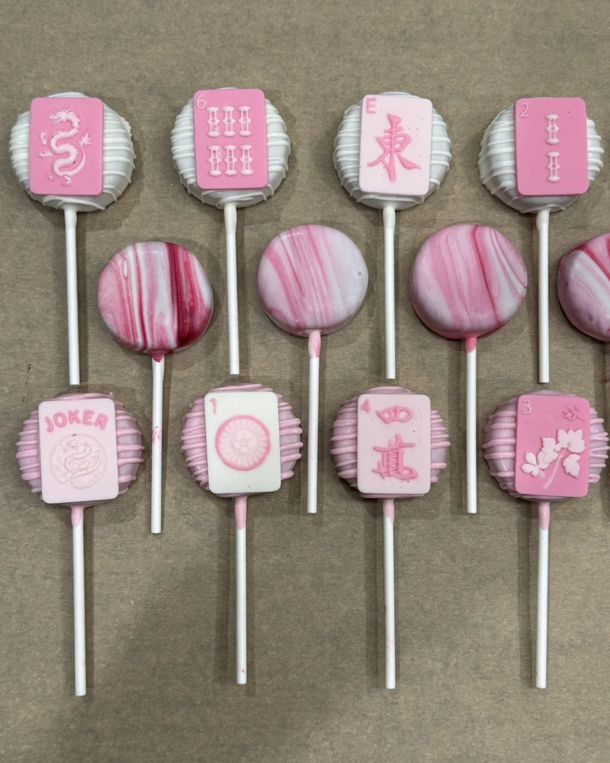 Mahjong-themed pink cake pops arranged in rows